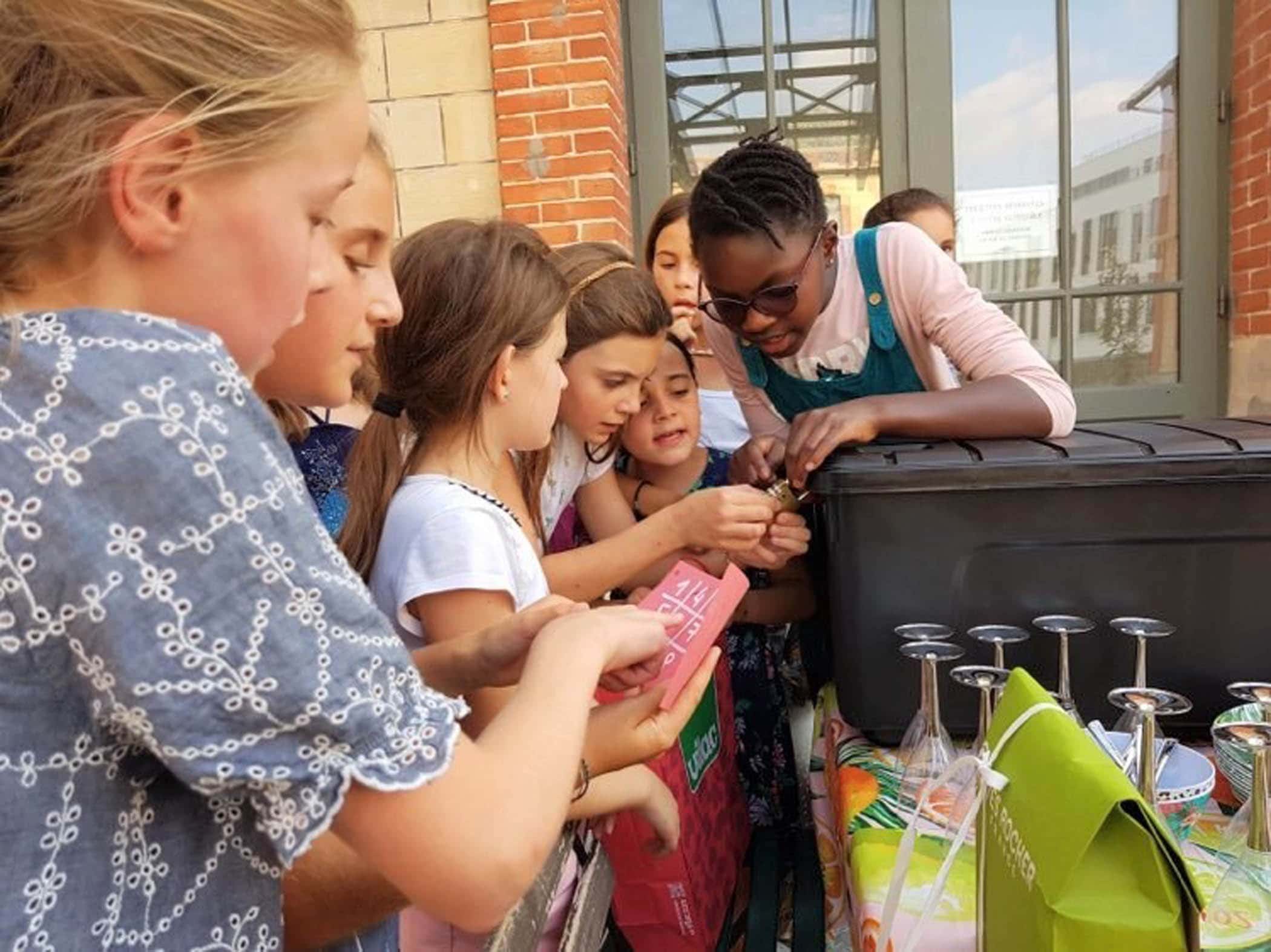 Un groupe de petites filles agées de 7 ans à 9 ans essayent d'ouvrir une boîte dans laquelle se trouve leur goûter d'anniversaire