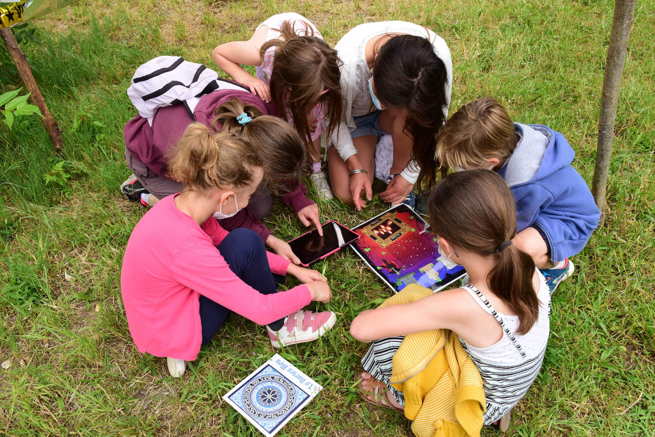 Un groupe d'enfants de centre de loisirs essaye de résoudre une énigme sur une tablette lors d'un Escape Game