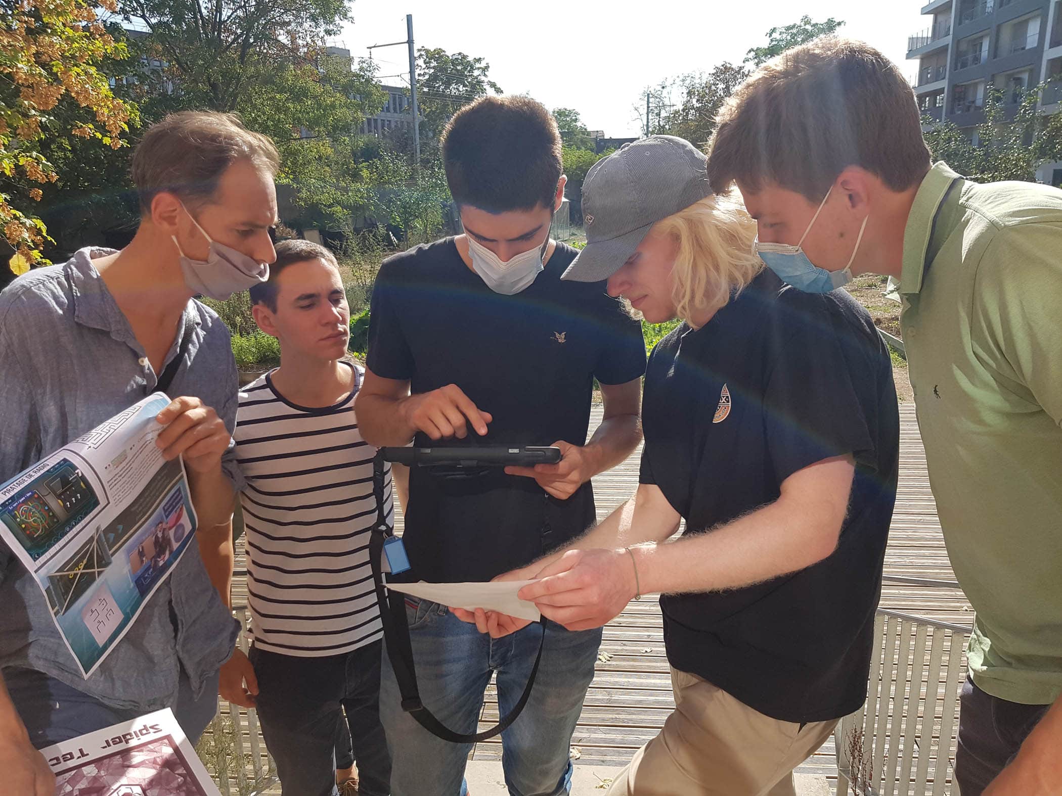 Un groupe d'amis venu pour un enterrement de vie de garçon résolvent une énigme sur une tablette tactile dans le jardin du château de Nanterre