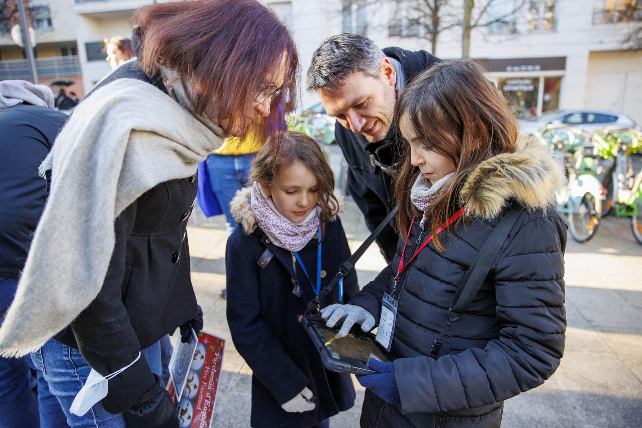 Une famille résout une énigme à l'aide d'une tablette numérique lors de la fête de ville de Rueil