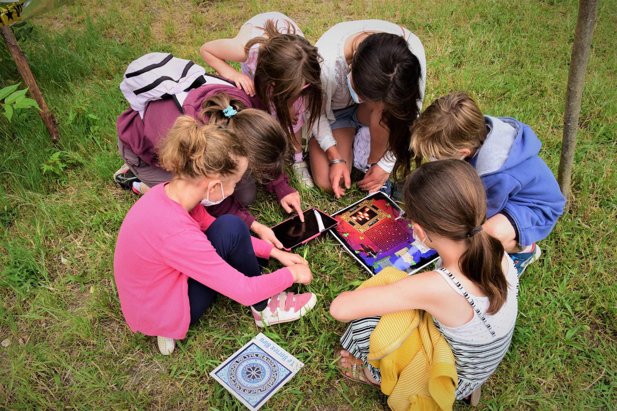 Plusieurs enfants sont regroupés autour d'une tablette afin de résoudre une énigme en réalité augmentée lors d'un jeu de piste dans les Hauts-de-Seine