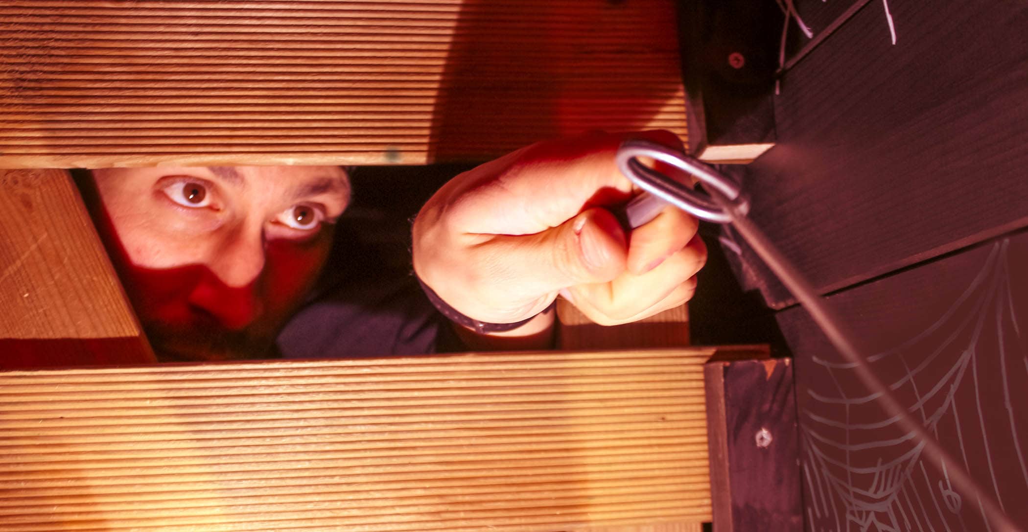 Un homme fait passer une clé à travers des planches de bois pour s'échapper d'une escape room